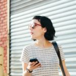 woman walking and looking at her phone featured image