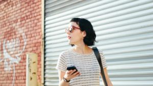 woman walking and looking at her phone featured image