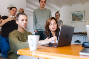 Co-workers surrounding a computer during a meeting featured image