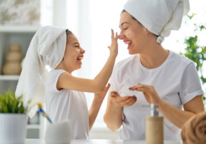 happy-mother-and-daughter-applying-face-cream
